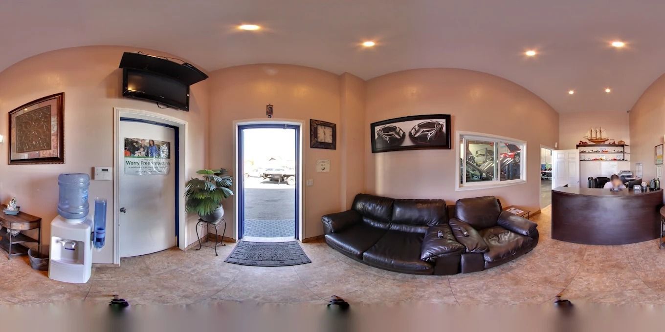Panoramic living room with black leather sectional, open doorway, wall art, and kitchen view