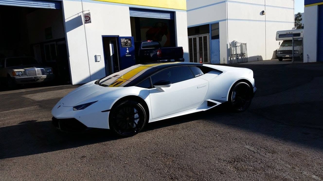 White sports car parked outside a building in bright sunlight.