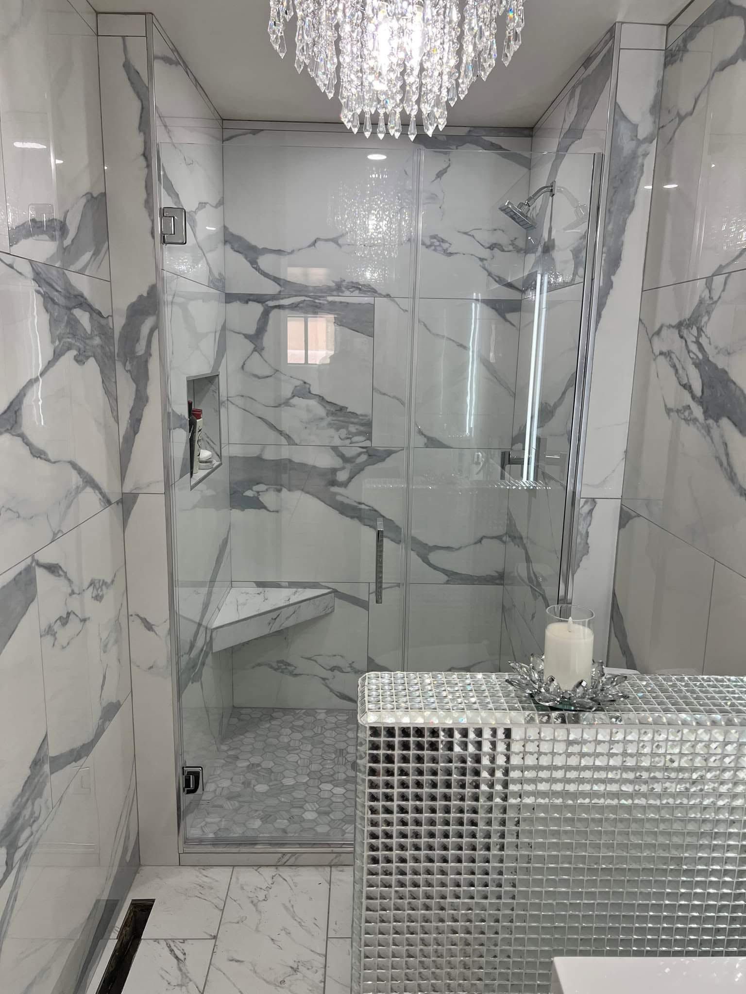 Marble-tiled luxury bathroom with a crystal chandelier and mirrored vanity counter
