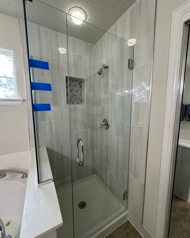Glass shower stall with chrome fixtures in a tiled bathroom