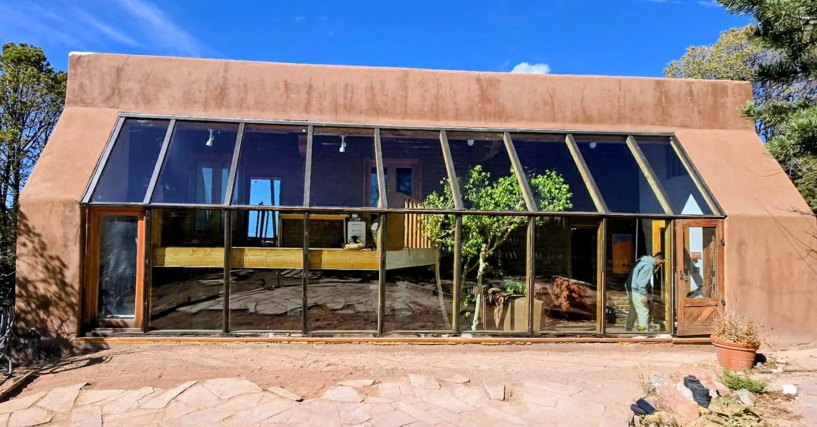 Modern adobe-style building with reflective glass facade and desert landscaping under a blue sky
