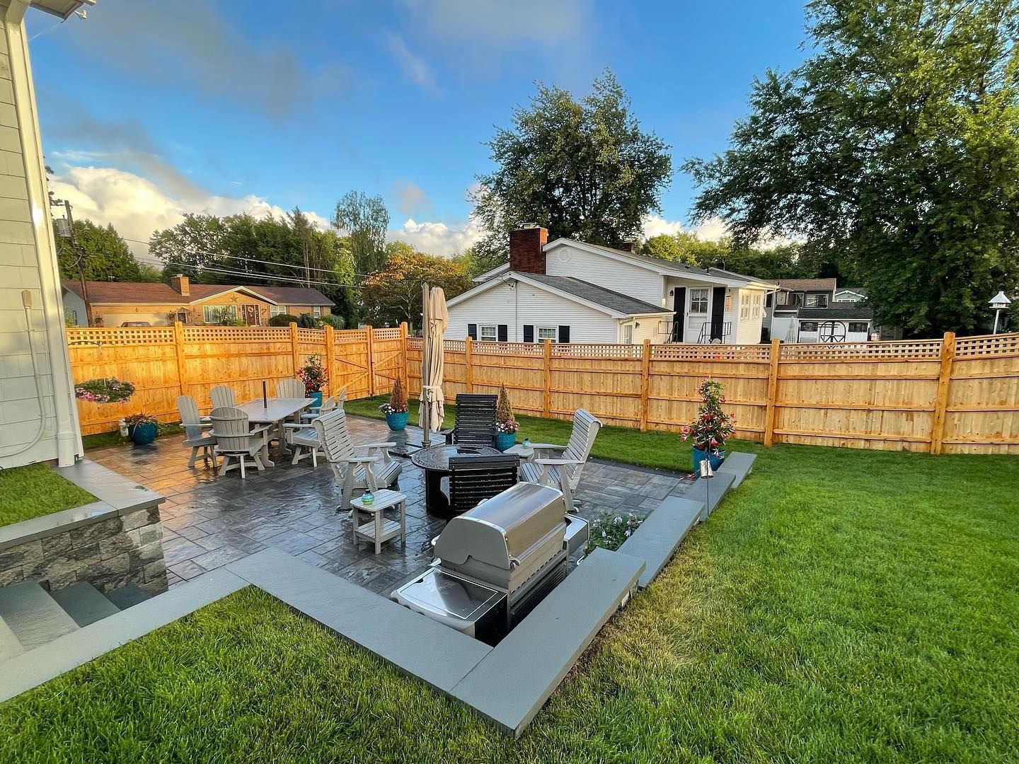 A backyard with a grill , table and chairs and a wooden fence.
