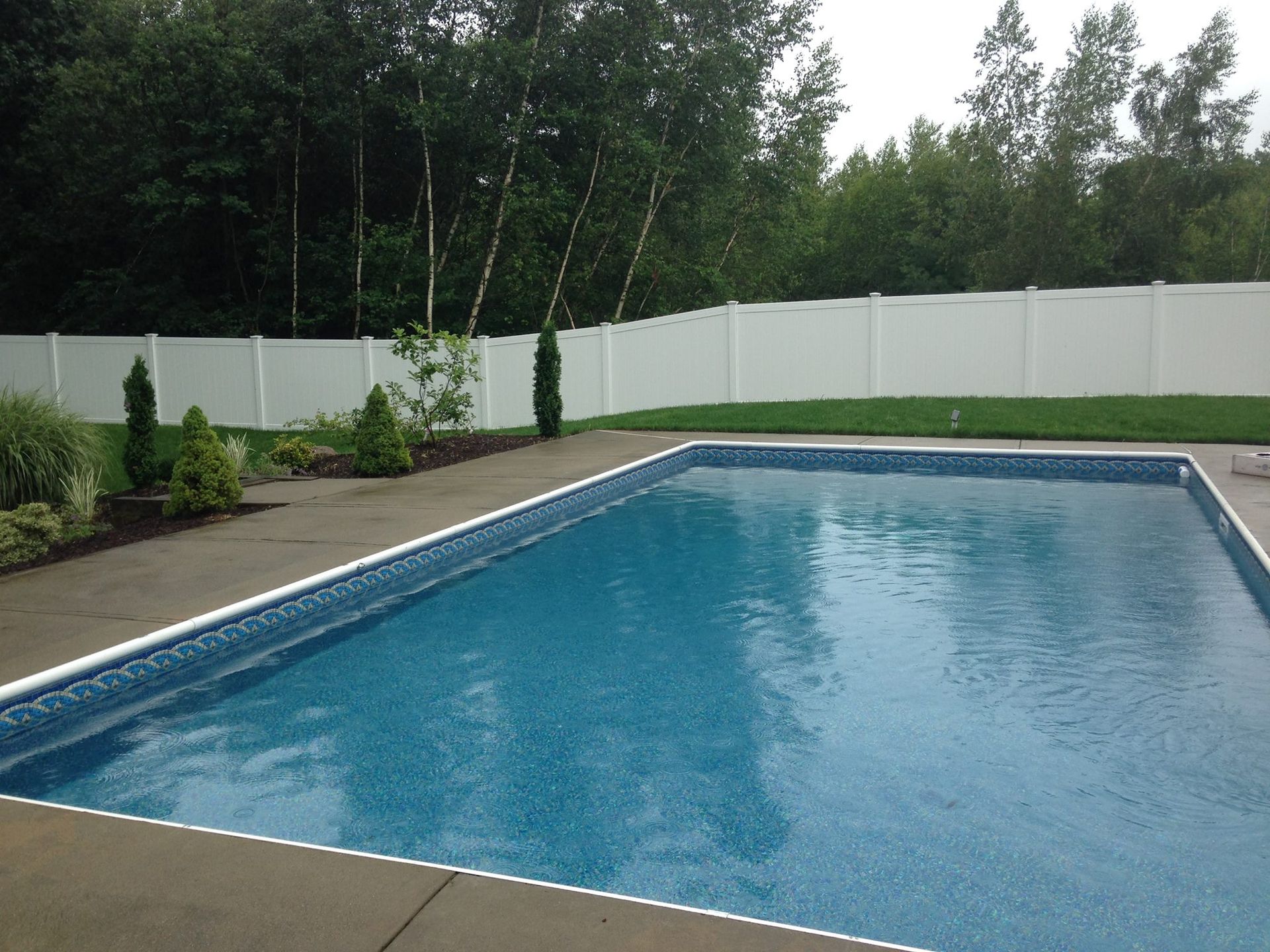 A large swimming pool with a white fence surrounding it