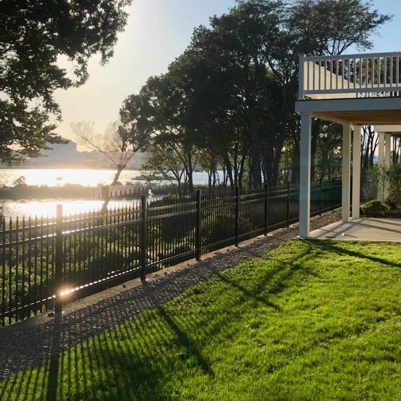A fence surrounds a house with a view of a lake