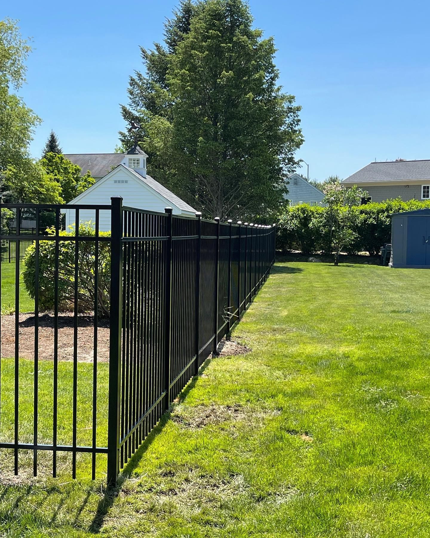 A black metal fence surrounds a lush green yard.