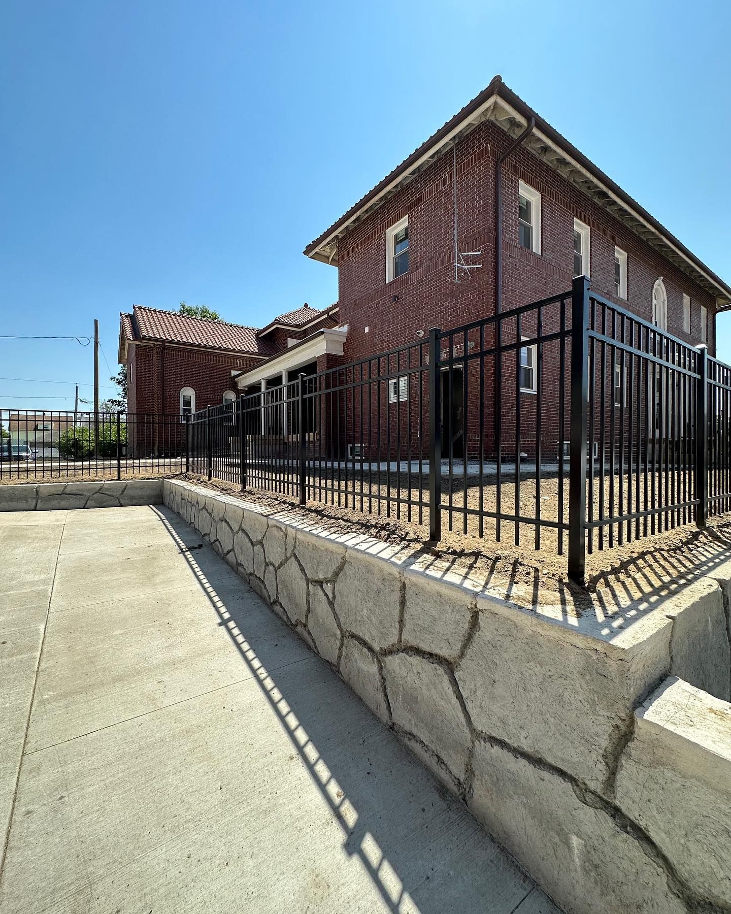 A brick building with a black fence around it