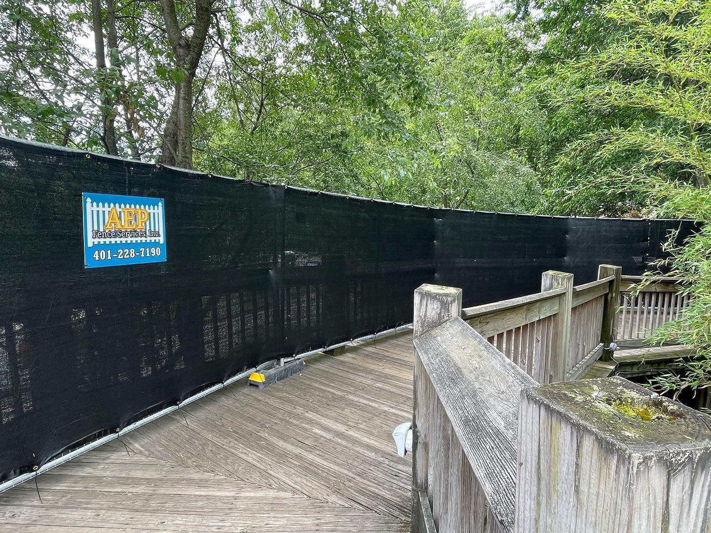 A black fence surrounds a wooden bridge in a park.
