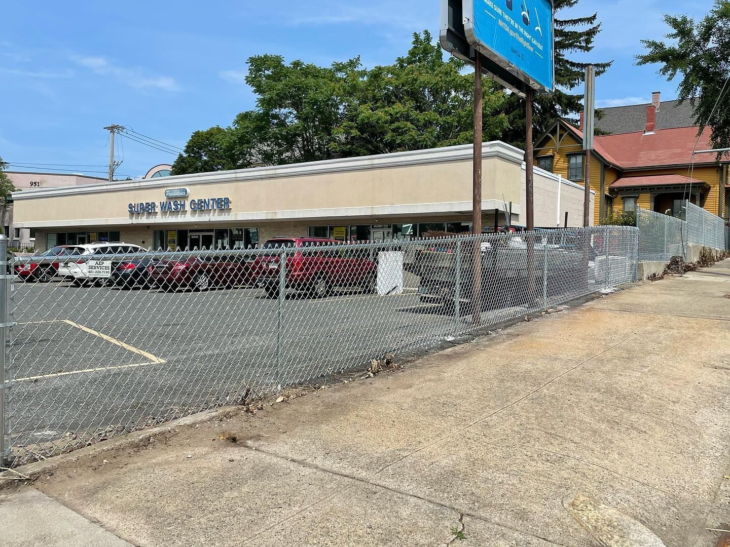 A chain link fence surrounds a parking lot in front of a building.