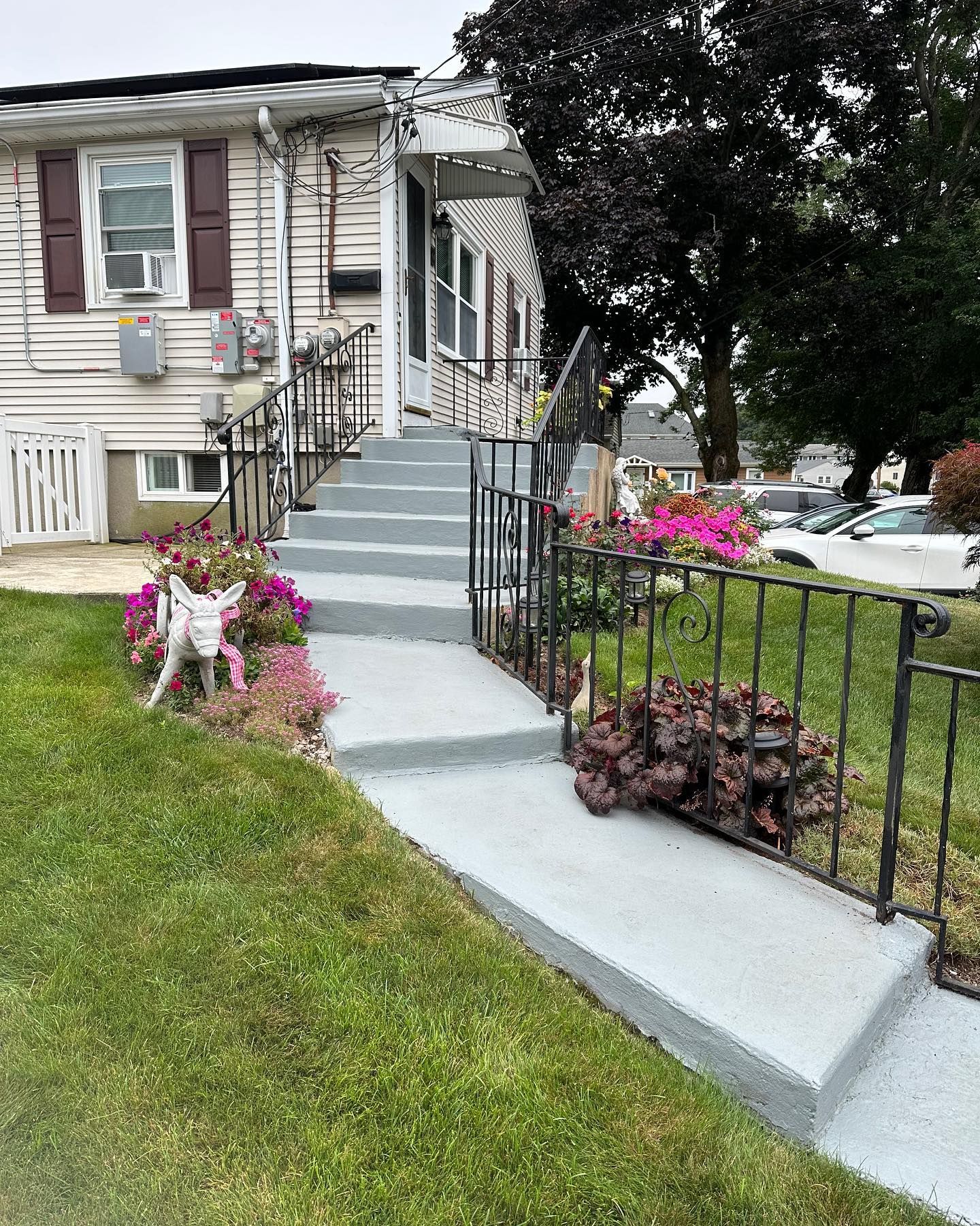 A concrete walkway leading to a house with stairs leading up to it.