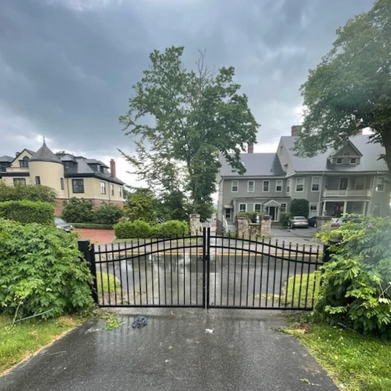 A gated driveway leading to a house on a cloudy day