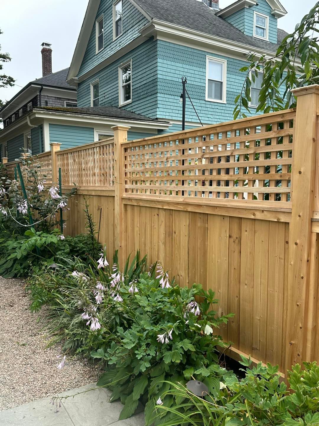 A wooden fence is in front of a blue house.