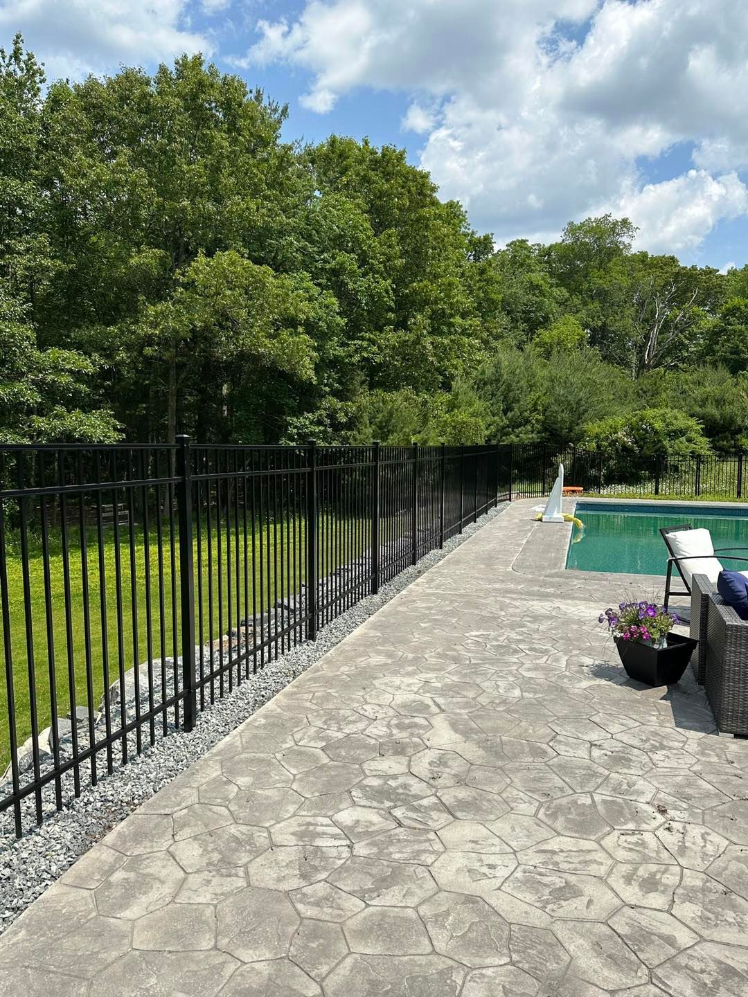 A fence surrounds a swimming pool in a backyard.