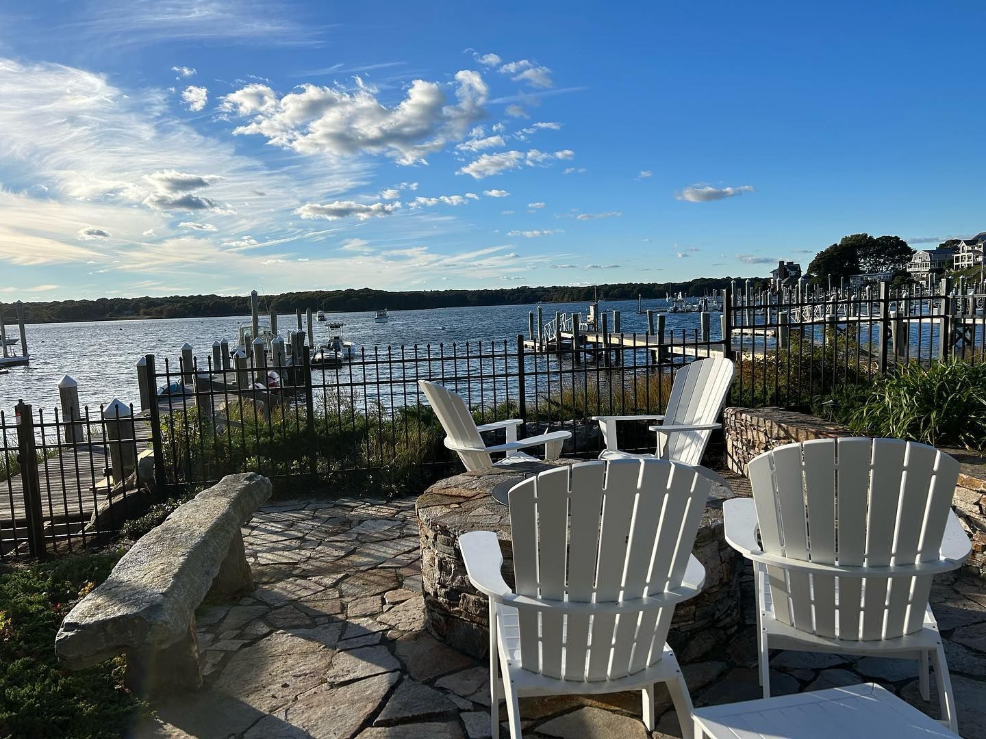 Two white adirondack chairs are sitting on a patio overlooking a body of water.