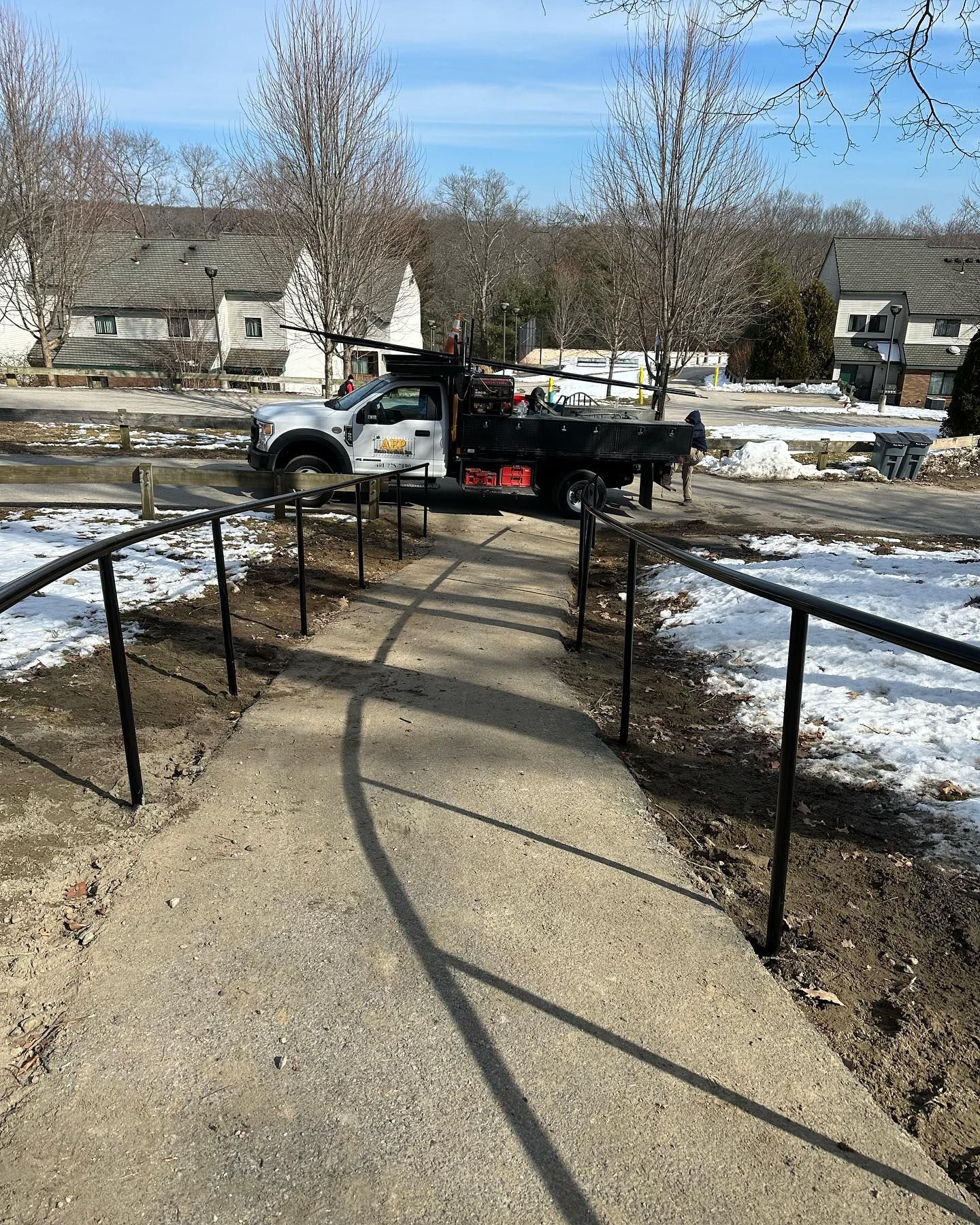 A truck is parked on the side of a sidewalk next to a staircase.