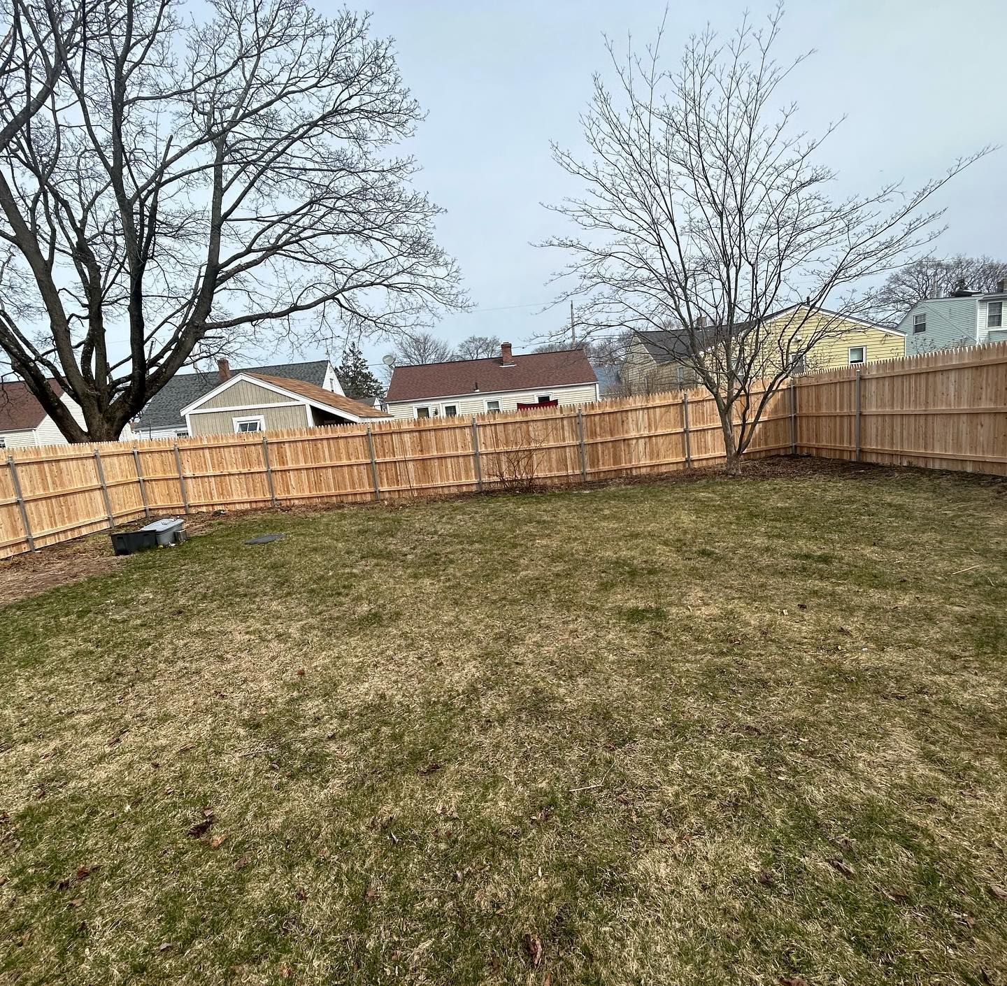 A backyard with a wooden fence and trees in the background.