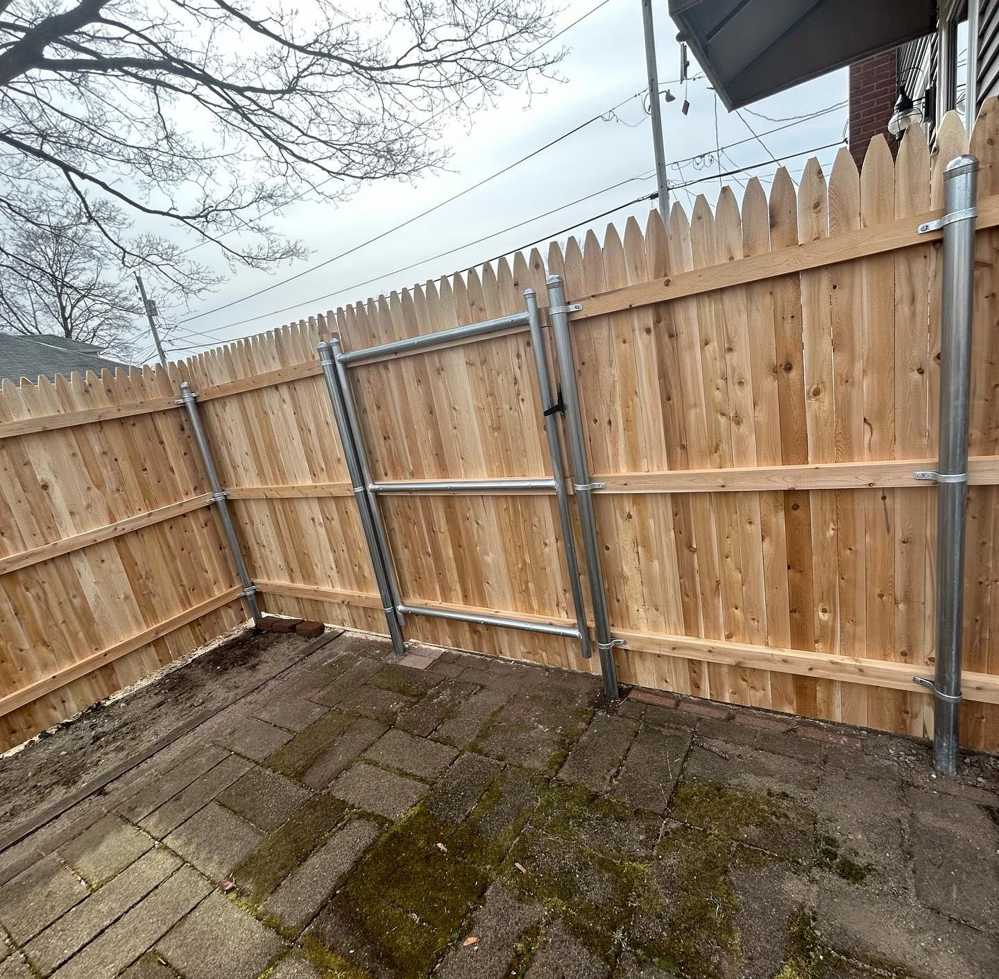 A wooden fence with a metal gate in the backyard.