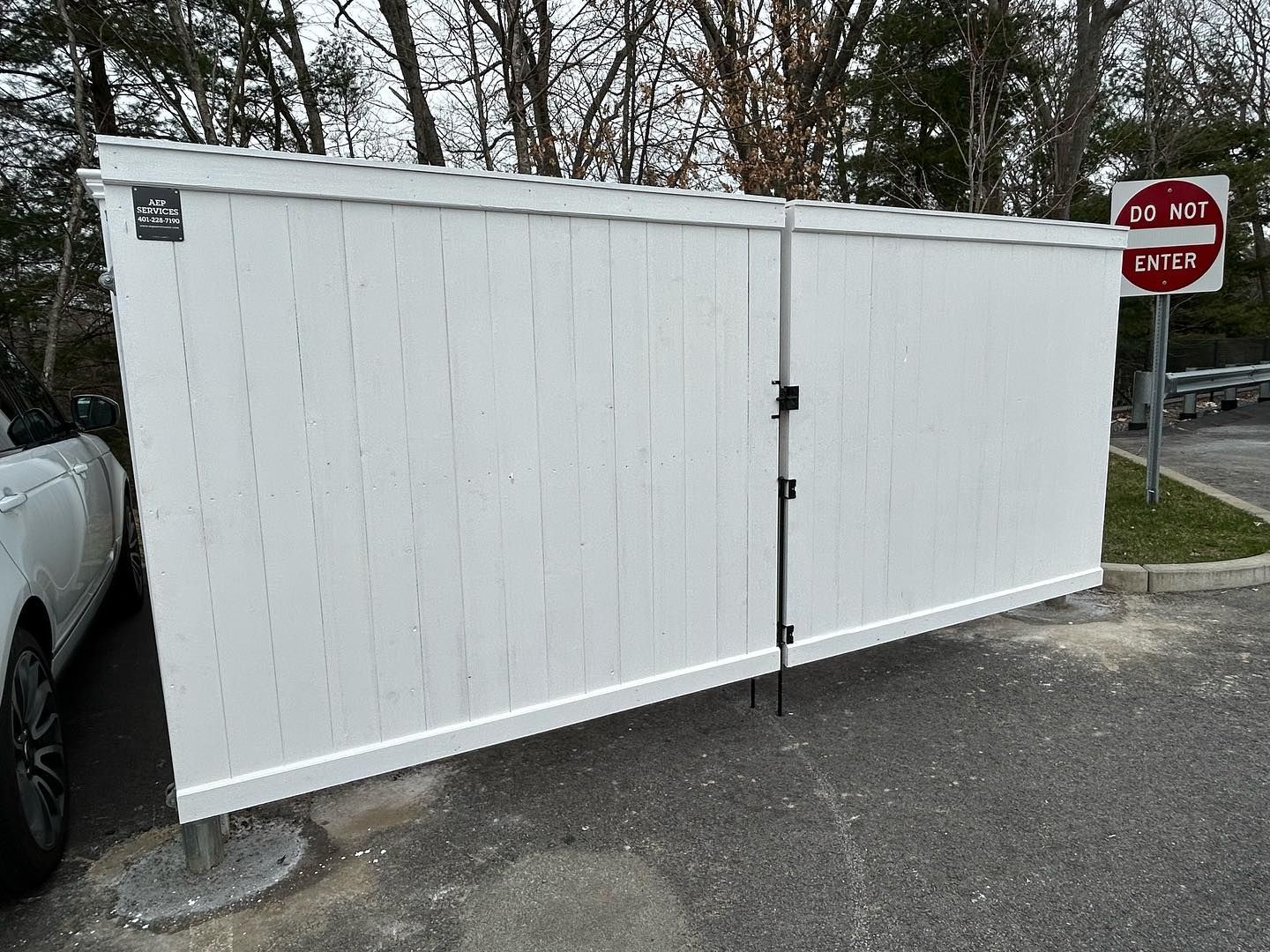 A white fence is sitting in a parking lot next to a do not enter sign.