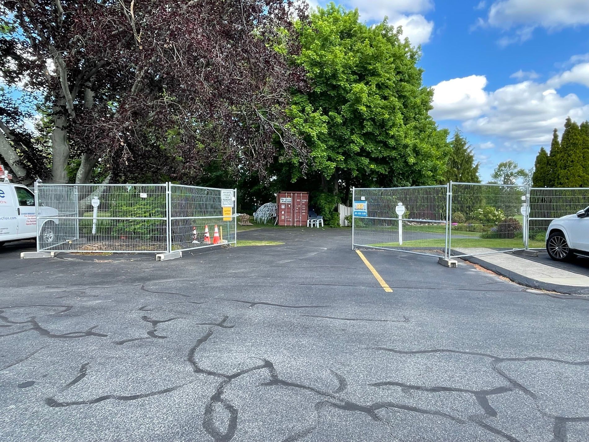 A parking lot with a fence and trees in the background.