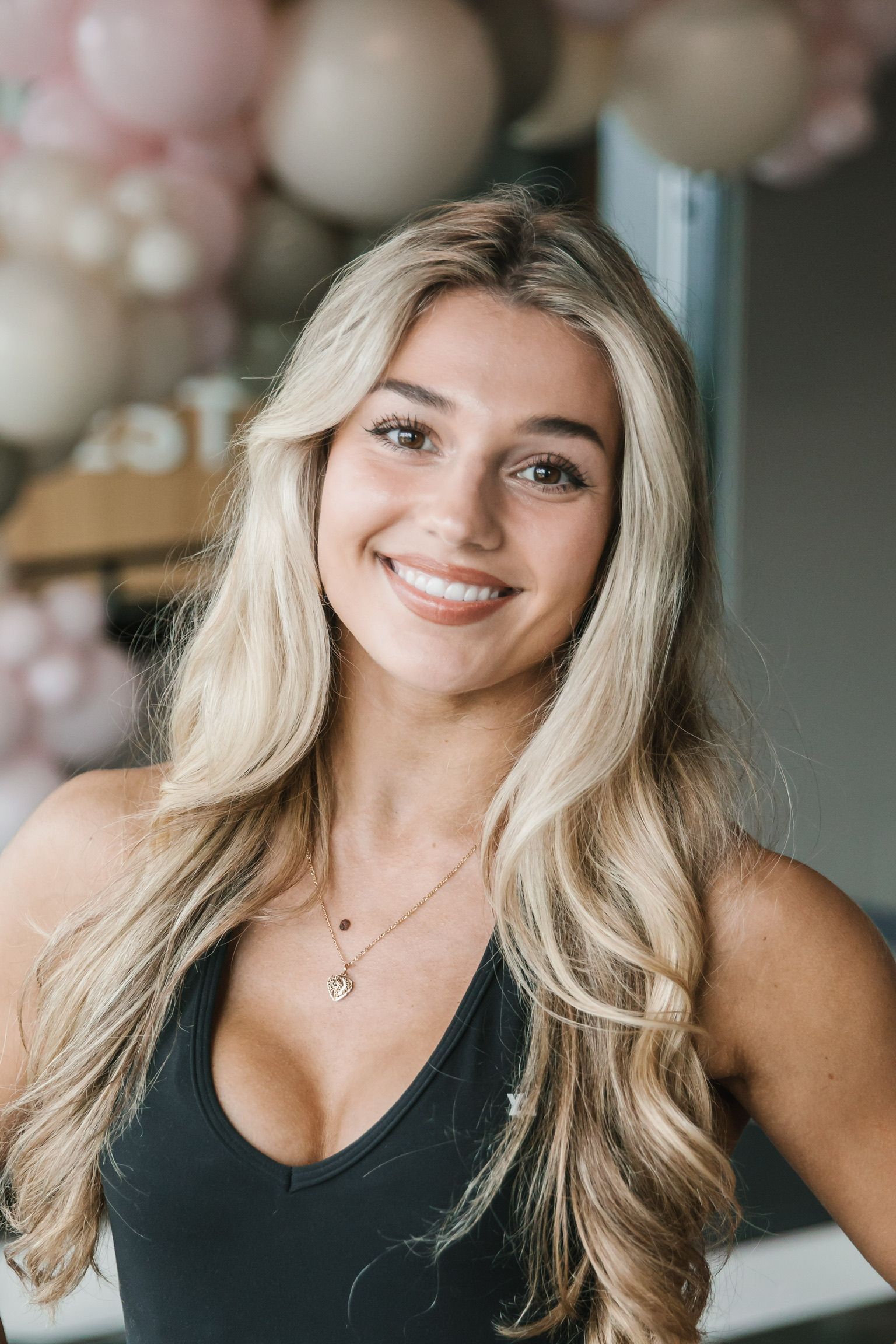 A woman wearing a black shirt and a necklace is smiling for the camera.