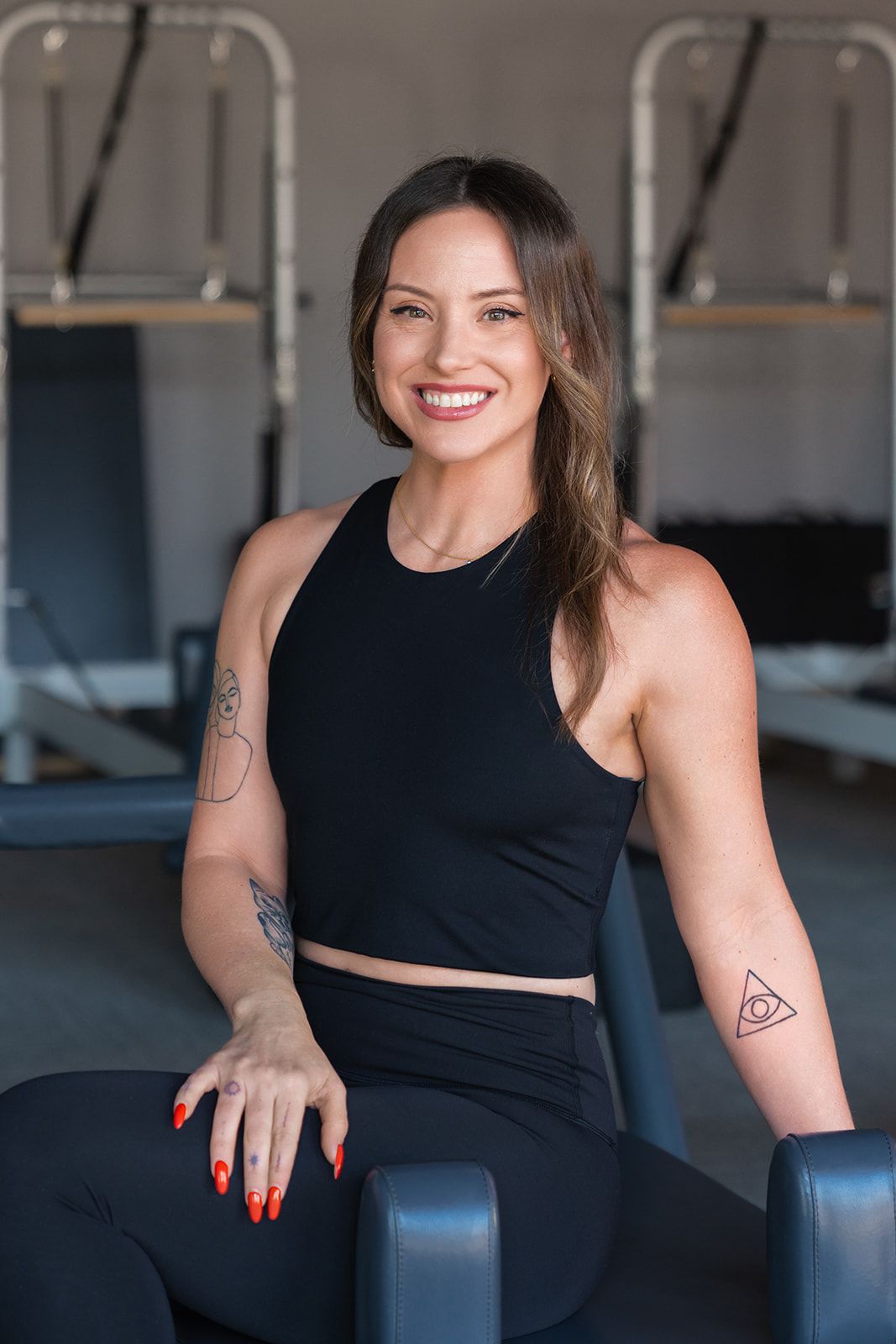 A woman is sitting on a yoga mat in a gym.