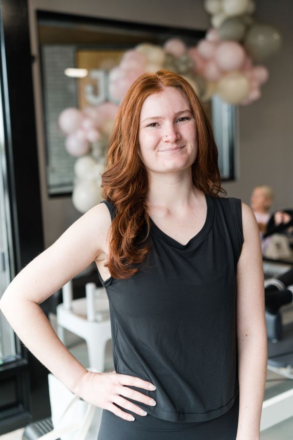 A woman wearing a black shirt and a necklace is smiling for the camera.