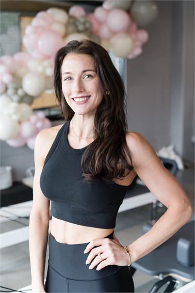 A woman wearing a black shirt and a necklace is smiling for the camera.