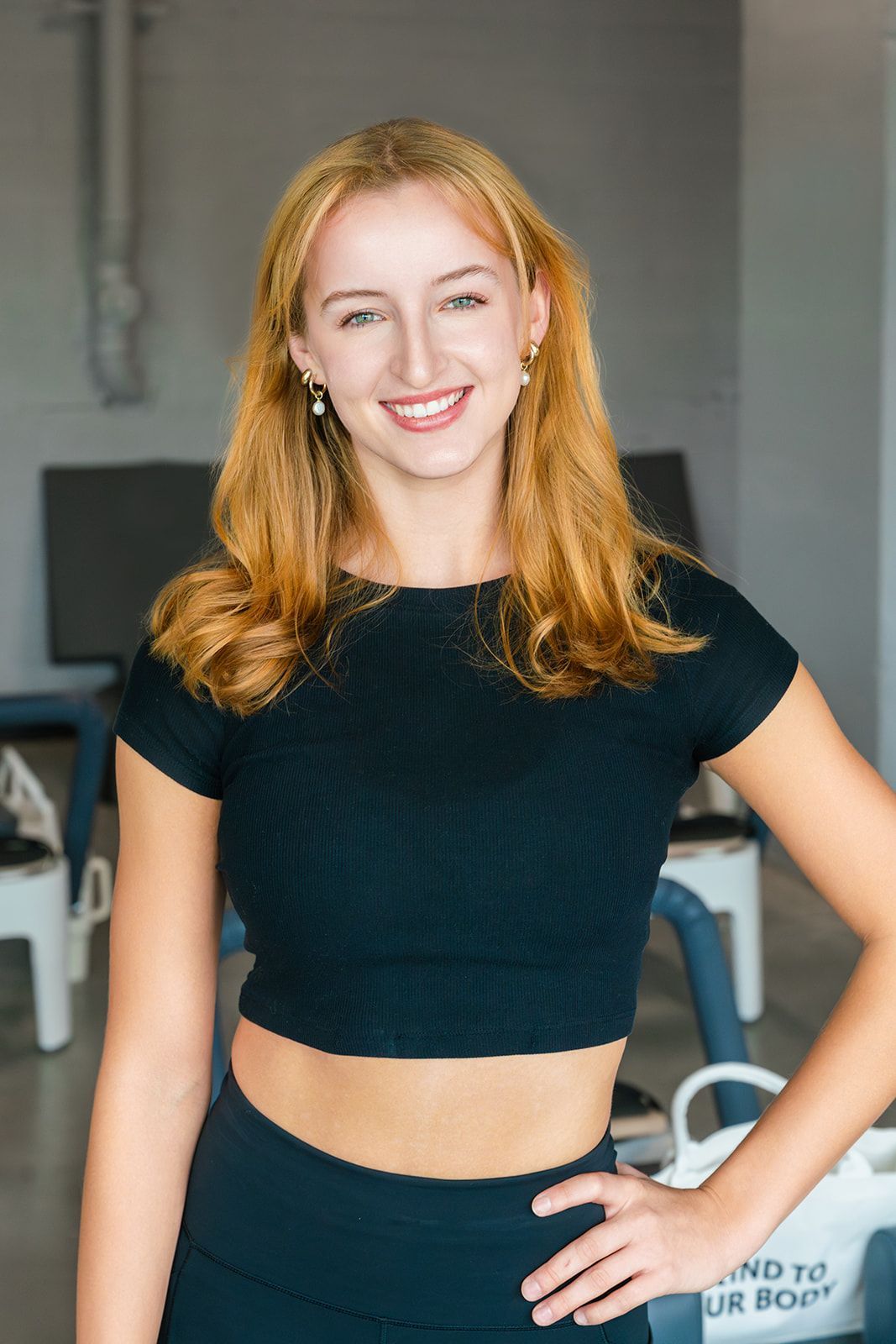 A woman is sitting on a yoga mat in a gym.