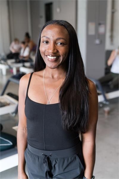A woman wearing a black shirt and a necklace is smiling for the camera.