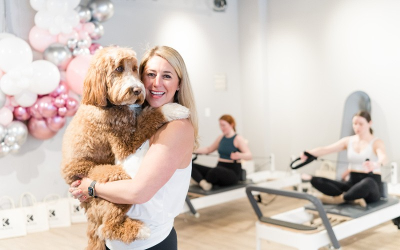 A woman is holding a dog in her arms in a gym.