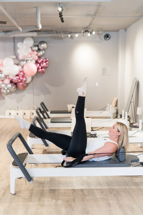 A woman is doing pilates on a pilates machine in a gym.