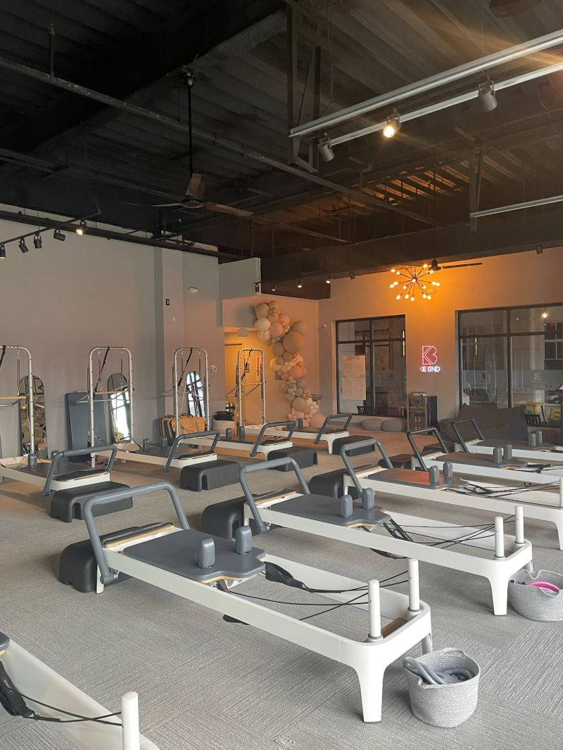 Pilates studio with exercise equipment, light-colored floors, and a neutral color scheme.