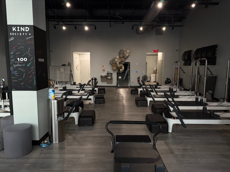 Pilates studio with gray equipment, mirrored walls, and a welcoming atmosphere.