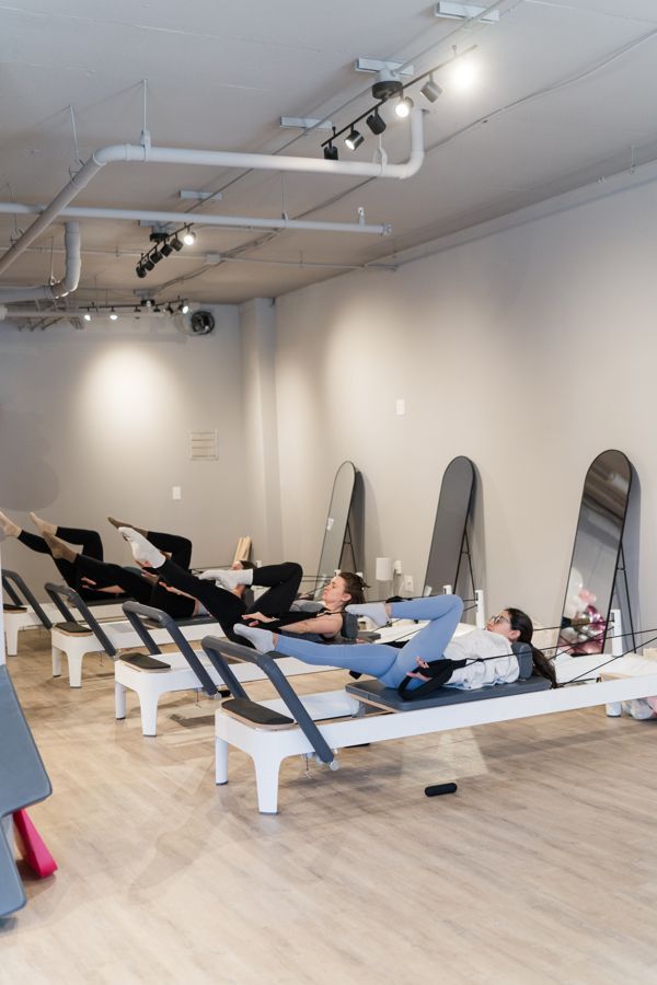 A woman is laying on a pilates machine in a gym.