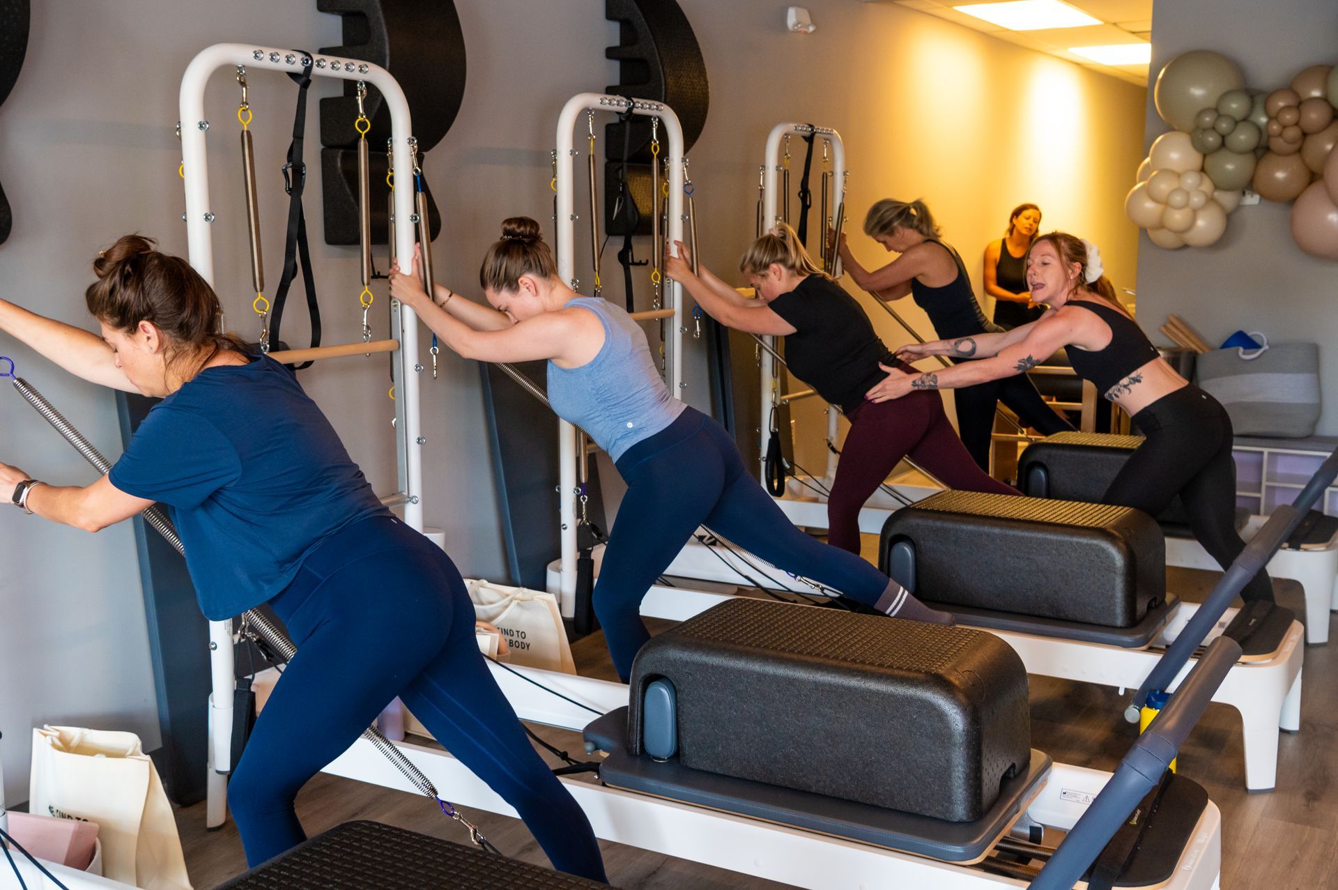 A group of women are doing exercises on pilates machines in a gym.