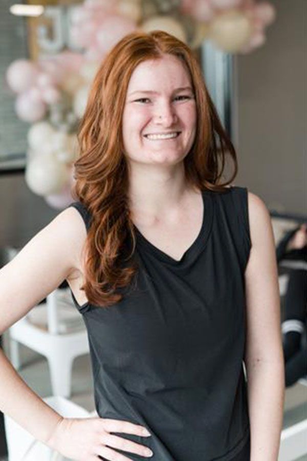 A woman is sitting on a yoga mat in a gym.