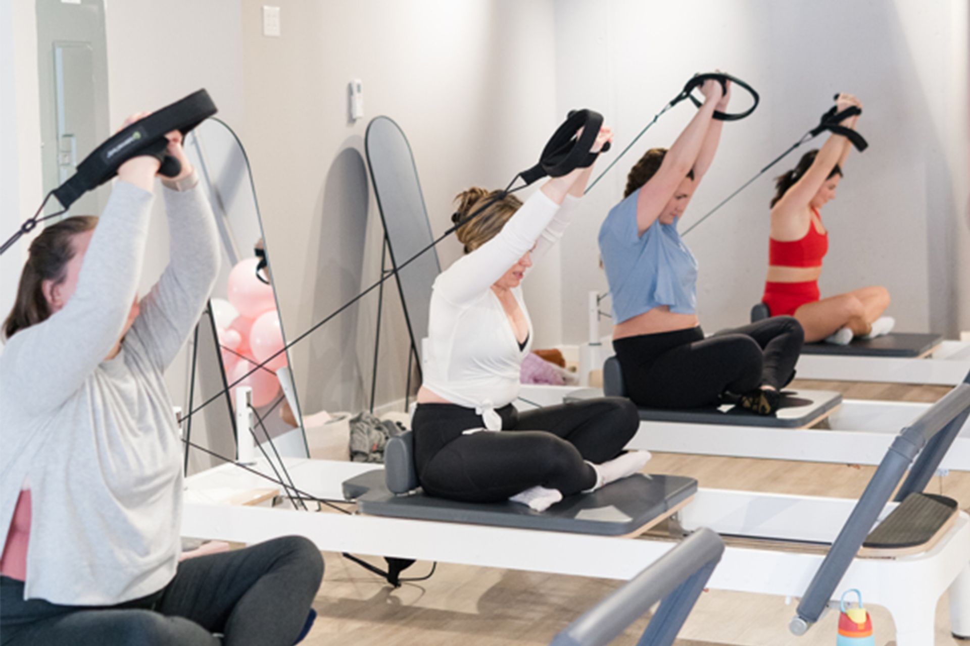 Group of people performing seated resistance-band stretches in a bright fitness studio.
