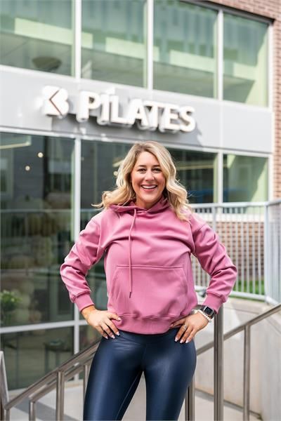 A woman is sitting on a yoga mat in a gym.