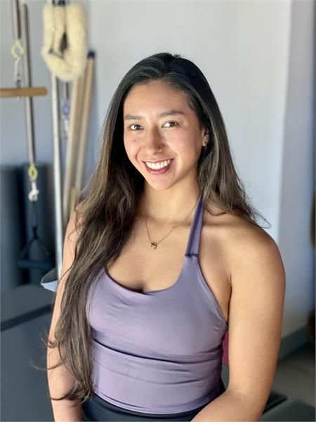 A woman wearing a black shirt and a necklace is smiling for the camera.