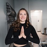 A woman is standing in a kitchen with her hands folded in prayer.