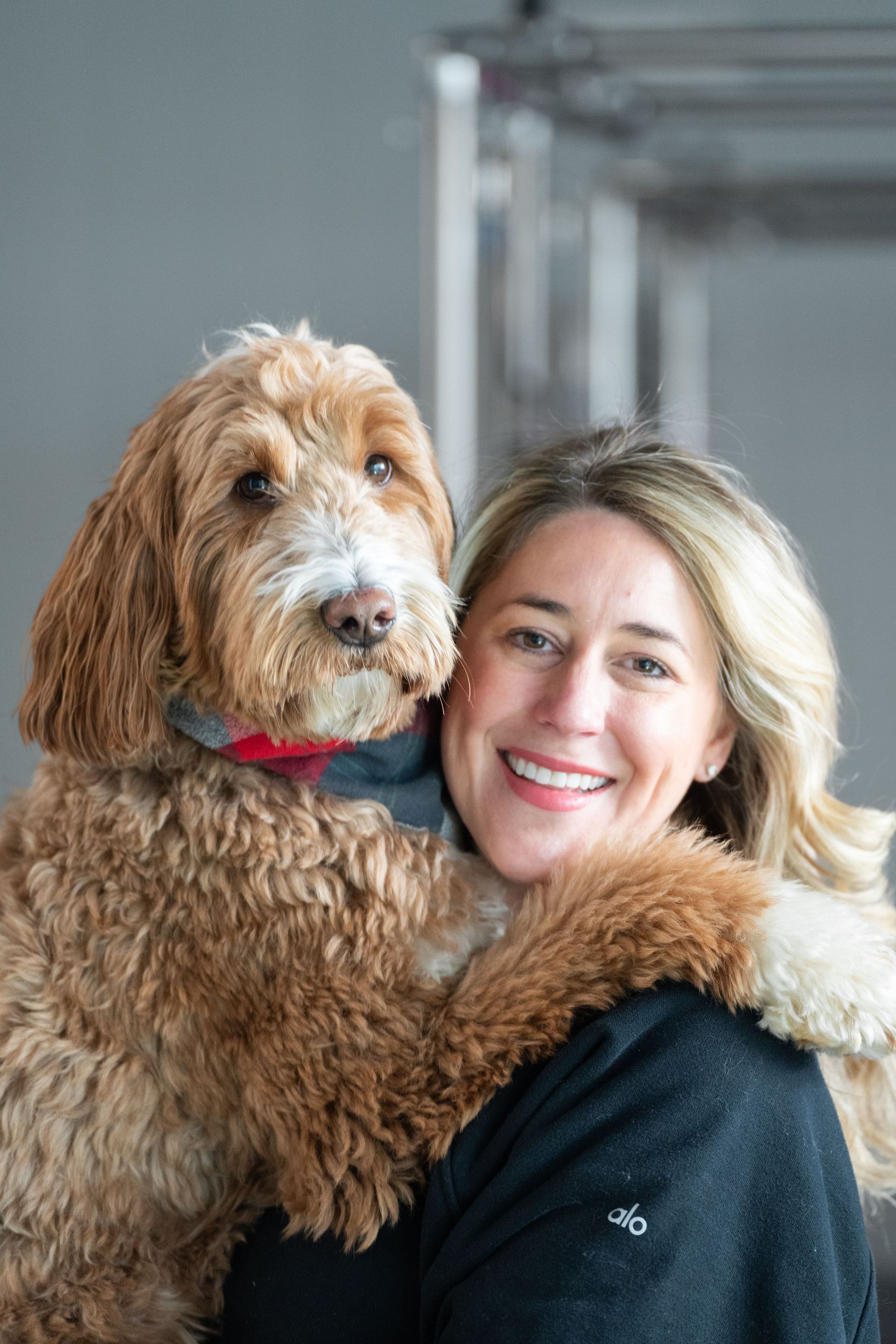 A woman is holding a brown dog in her arms.