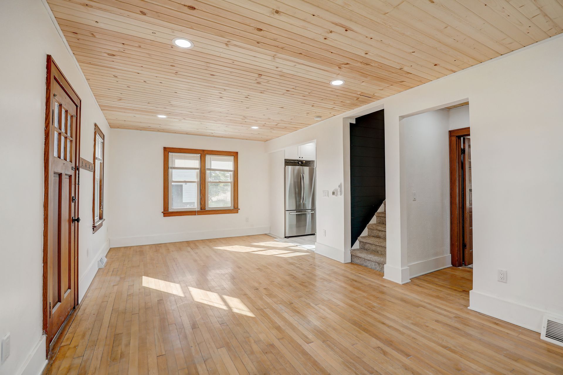 Empty room with wood ceiling, floors, and trim, white walls.