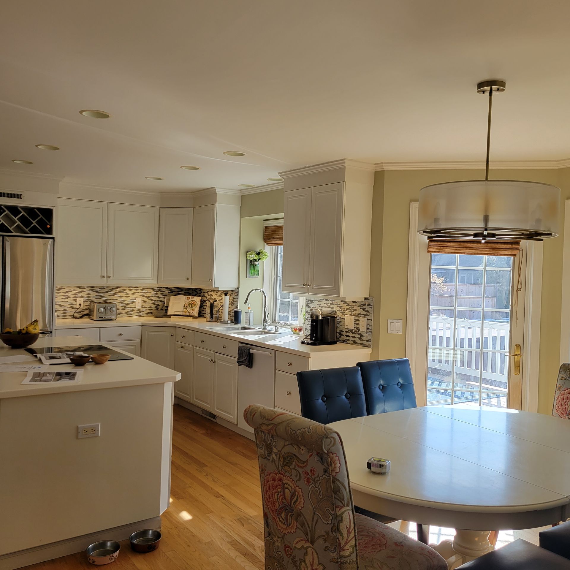 White kitchen with a dining area. Sunlight streams through a back door.