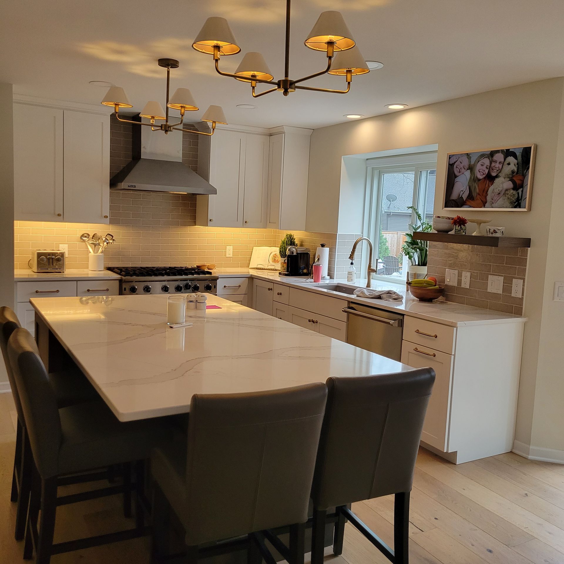 Modern kitchen with white cabinets, a large island with seating, and a stone backsplash.