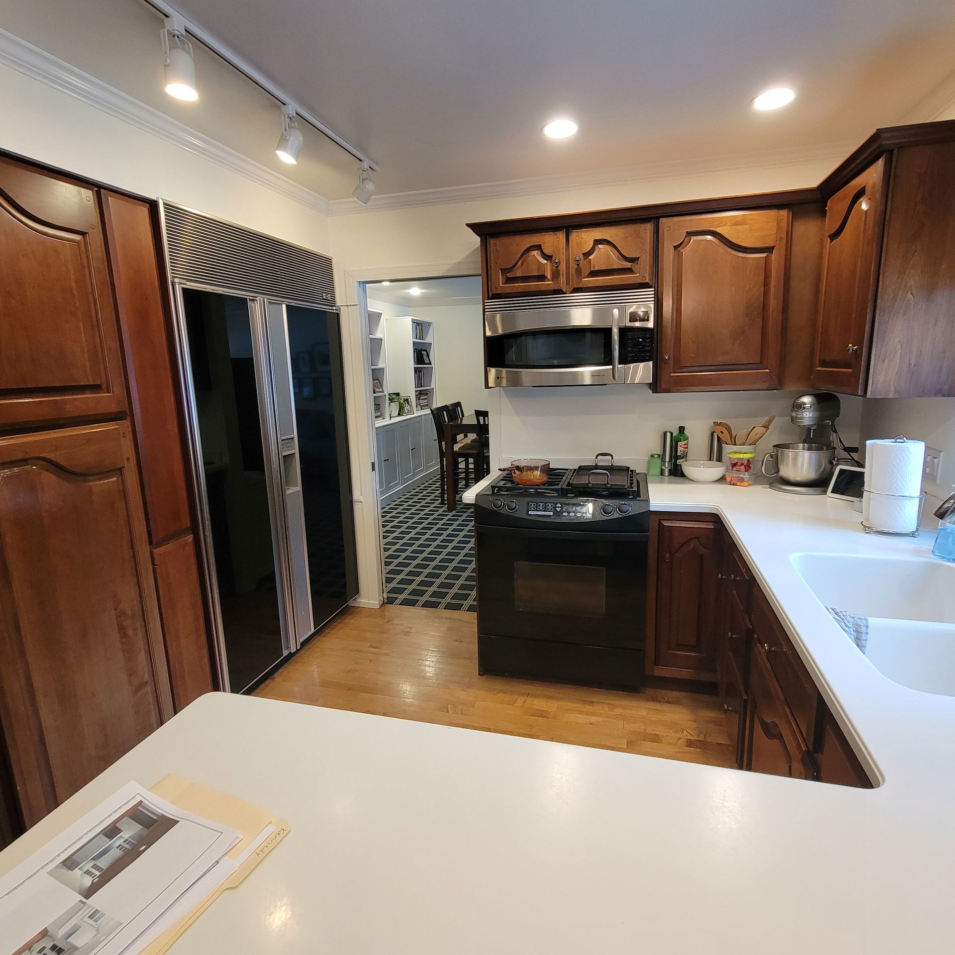 Kitchen with dark wood cabinets, stainless steel appliances, and a white countertop.