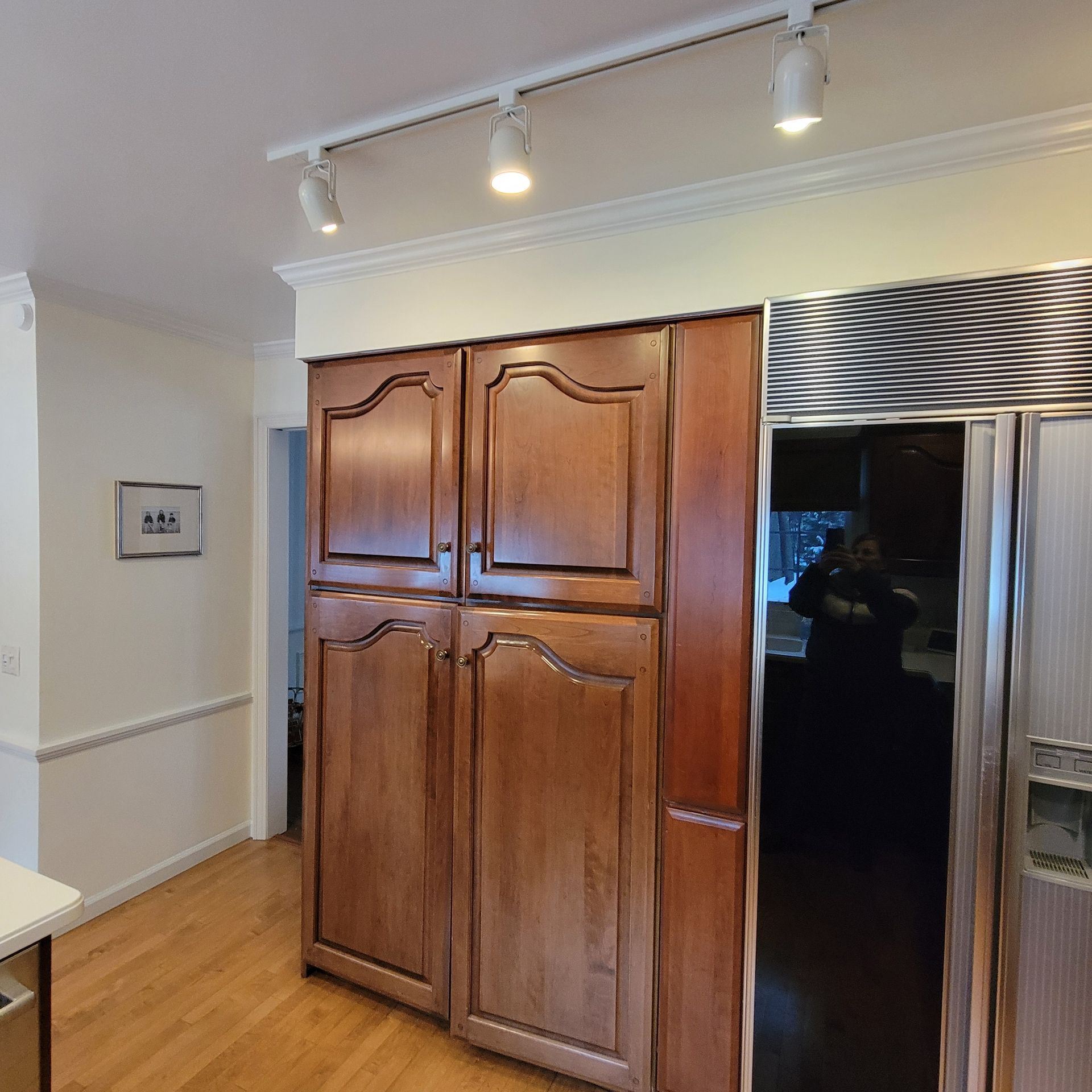 Kitchen with wooden cabinets, refrigerator, and track lighting.