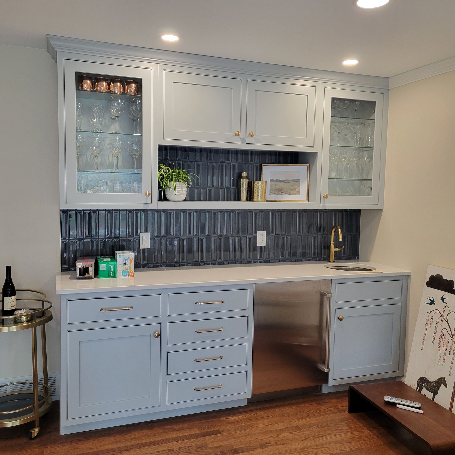 Built-in home bar with blue cabinets, a white countertop, and a dark blue tile backsplash.
