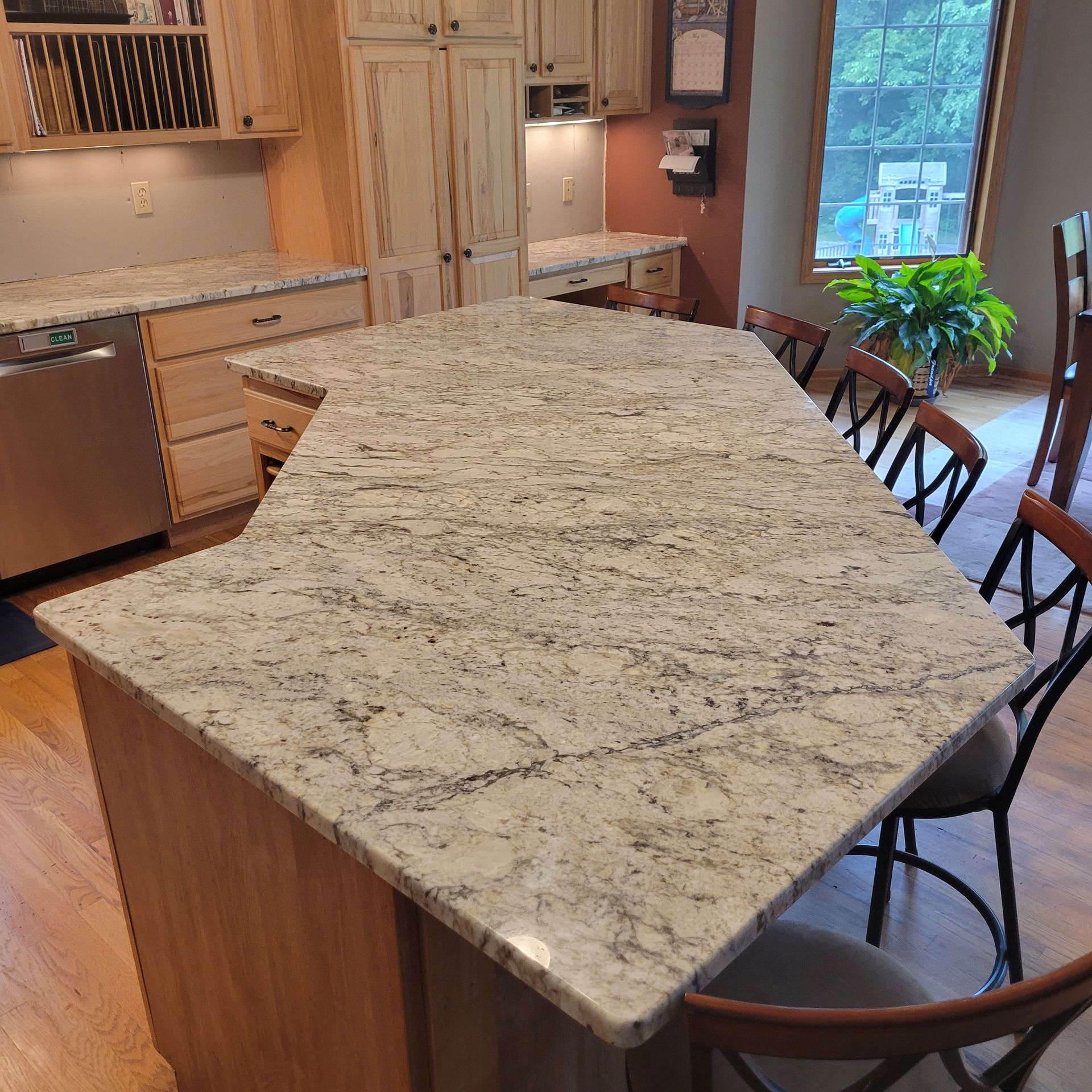 Kitchen with light wood cabinets and granite countertops, featuring a large island with seating.