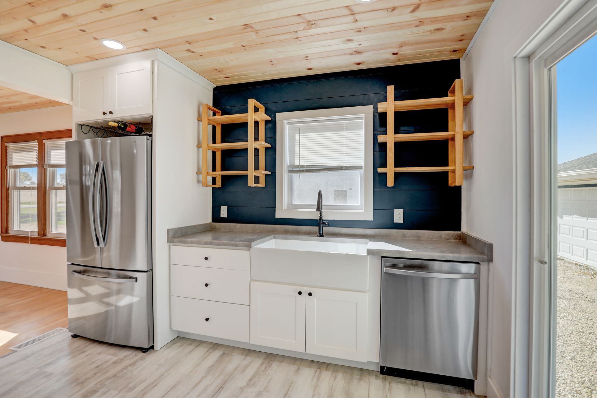 Kitchen with white cabinets, stainless steel appliances, wood shelves, and a blue wall.