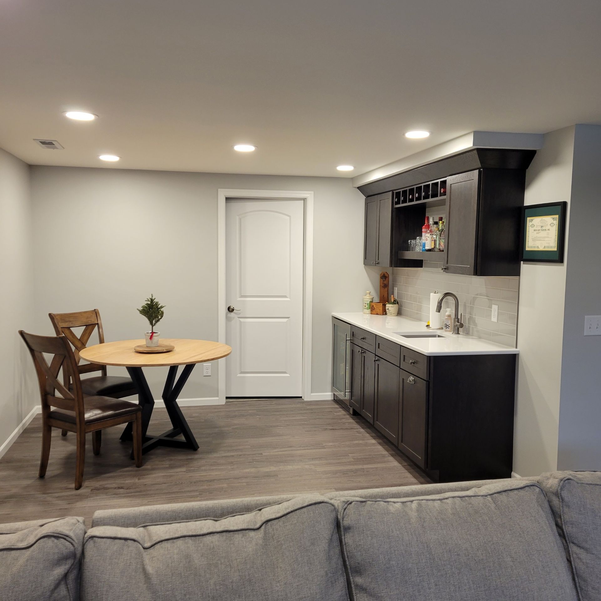 Basement with a small dining table, built-in bar, and gray flooring.