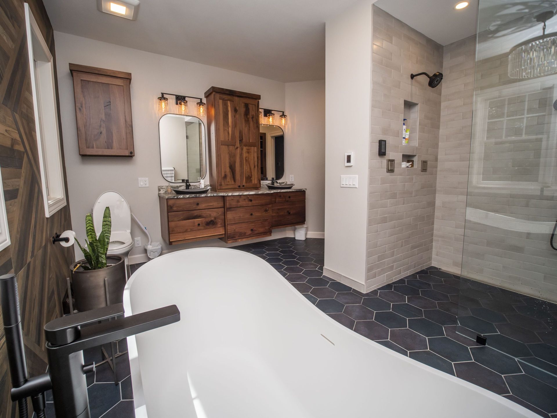 Modern bathroom with a freestanding tub, wooden vanity, and tiled shower.